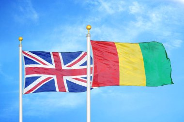 Birleşik Krallık ve Gine bayrak direkleri üzerinde iki bayrak ve mavi bulutlu arka plan