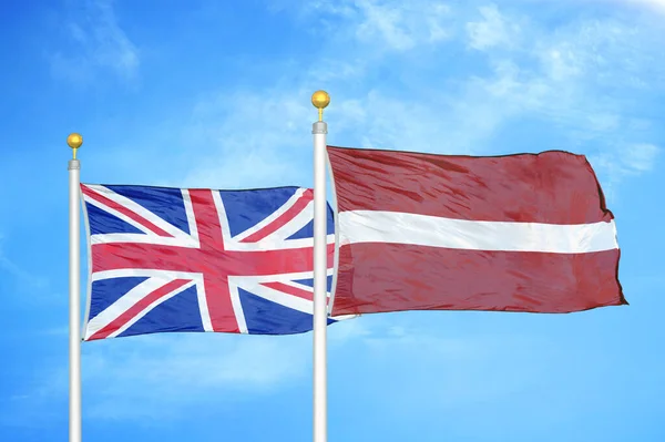 イギリスとラトビアの旗竿と青空の背景に2つの旗 — ストック写真