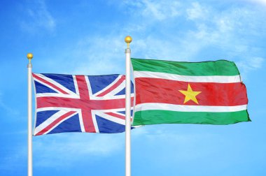 Birleşik Krallık ve Surinam bayrak direkleri ve mavi bulutlu arka planda iki bayrak