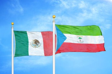 Meksika ve Ekvator Ginesi bayrak direkleri üzerinde iki bayrak ve mavi bulutlu gökyüzü arka planı