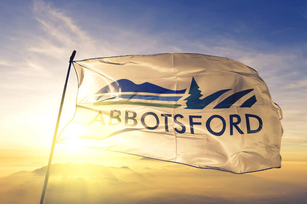 Абботсфорд, Британская Колумбия, Канада, флаг текстильной ткани ткани размахивая на вершине тумана восхода солнца
