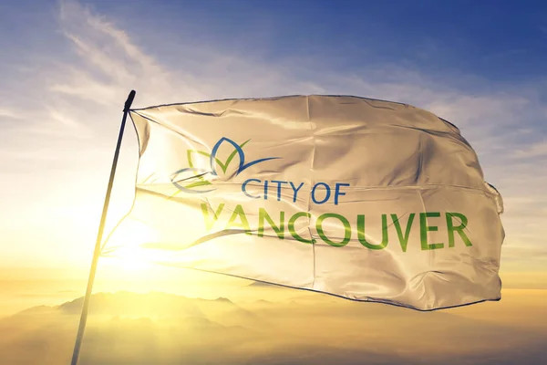 Vancouver of British Columbia of Canada flag textile cloth fabric waving on the top sunrise mist fog