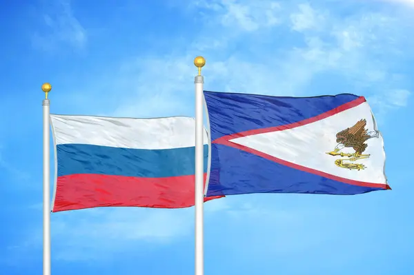 ロシアとアメリカサモアの旗竿と青空の背景に2つの旗 — ストック写真