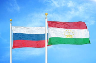 Rusya ve Tacikistan bayrak direkleri ve mavi bulutlu arka planda iki bayrak