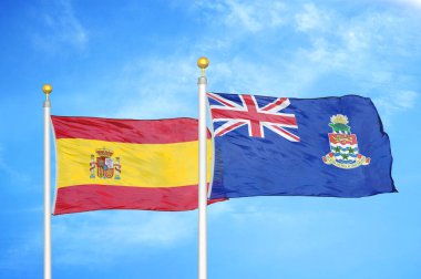 İspanya ve Cayman Adaları bayrak direkleri ve mavi bulutlu arka planda iki bayrak