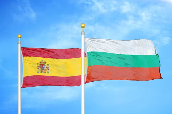 西班牙和保加利亚旗杆上的两面旗帜和蓝云天背景 — 图库照片