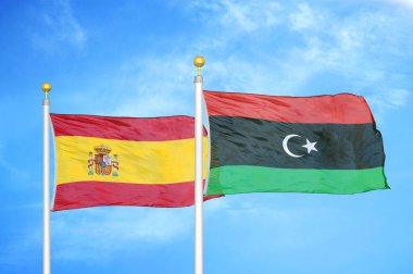İspanya ve Libya bayrak direkleri ve mavi bulutlu arka planda iki bayrak