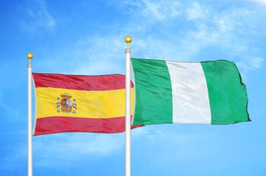 İspanya ve Nijerya bayrak direkleri üzerinde iki bayrak ve mavi bulutlu arka plan