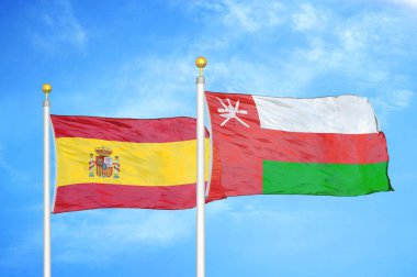 İspanya ve Umman bayrak direkleri ve mavi bulutlu arka planda iki bayrak