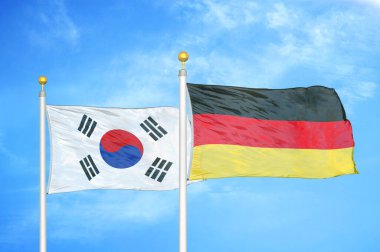 Güney Kore ve Almanya bayrak direkleri ve mavi bulutlu arka planda iki bayrak