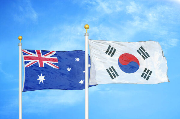 Австралия и Южная Корея два флага на флагштоках и голубом облачном фоне неба
