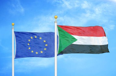 Avrupa Birliği ve Sudan bayrak direkleri ve mavi bulutlu arka planda iki bayrak