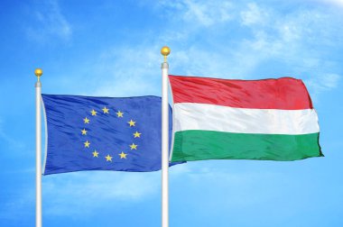 Avrupa Birliği ve Macaristan bayrak direkleri ve mavi bulutlu arka planda iki bayrak