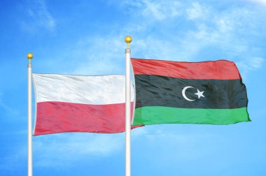 Polonya ve Libya bayrak direkleri ve mavi bulutlu arka planda iki bayrak