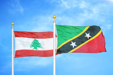 Lübnan ve Saint Kitts ve Nevis bayrak direğinde iki bayrak ve mavi bulutlu gökyüzü arka planı