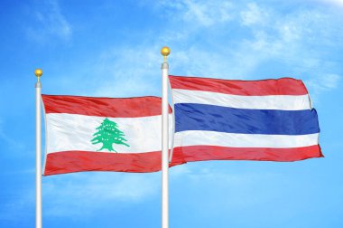 Lübnan ve Tayland bayrak direkleri ve mavi bulutlu arka planda iki bayrak