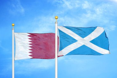 Katar ve İskoçya bayrak direkleri ve mavi bulutlu arka planda iki bayrak