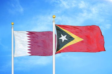 Katar ve Timor-Leste Doğu Timor bayrak direkleri üzerinde iki bayrak ve mavi bulutlu arka plan