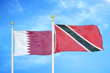 Katar, Trinidad ve Tobago bayrak direğinde iki bayrak ve mavi bulutlu gökyüzü arkaplanı