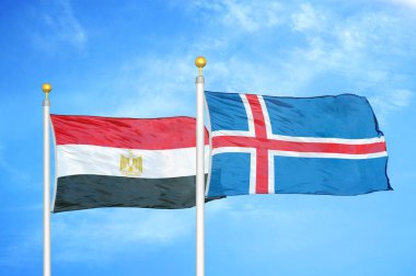 Mısır ve İzlanda bayrak direkleri ve mavi bulutlu arka planda iki bayrak