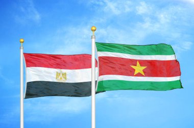 Mısır ve Surinam bayrak direkleri üzerinde iki bayrak ve mavi bulutlu arka plan