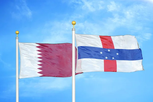 Qatar and Netherlands Antilles two flags on flagpoles and blue cloudy sky background