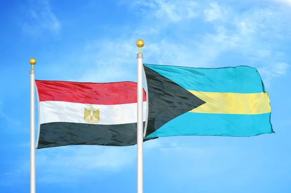 Egypt and Bahamas  two flags on flagpoles and blue cloudy sky background
