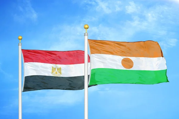 Egypt and Niger two flags on flagpoles and blue cloudy sky background