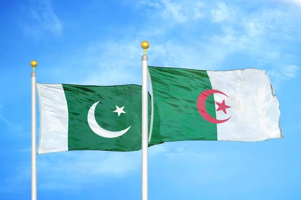 Pakistan and Algeria two flags on flagpoles and blue cloudy sky background