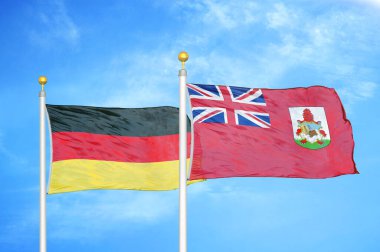 Almanya ve Bermuda bayrak direkleri ve mavi bulutlu arka planda iki bayrak