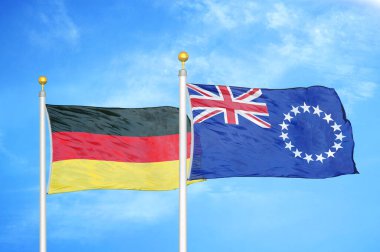 Almanya ve Cook Adaları bayrak direkleri ve mavi bulutlu arka planda iki bayrak