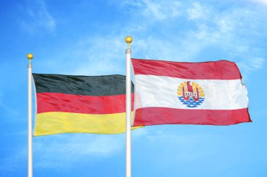 Almanya ve Fransız Polinezyası bayrak direkleri ve mavi bulutlu arka planda iki bayrak