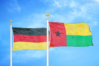 Almanya ve Gine-Bissau bayrak direkleri üzerinde iki bayrak ve mavi bulutlu arka plan