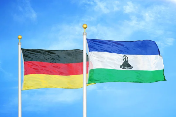德国和莱索托旗杆上的两面旗帜和蓝天背景 — 图库照片