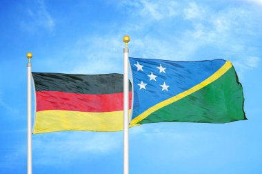 Almanya ve Solomon Adaları bayrak direkleri ve mavi bulutlu arka planda iki bayrak