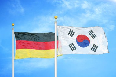 Almanya ve Güney Kore bayrak direkleri ve mavi bulutlu arka planda iki bayrak