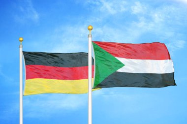 Almanya ve Sudan bayrak direkleri ve mavi bulutlu arka planda iki bayrak