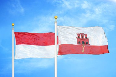 Endonezya ve Cebelitarık bayrak direkleri üzerinde iki bayrak ve mavi bulutlu arka plan