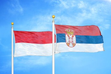 Endonezya ve Sırbistan bayrak direkleri ve mavi bulutlu arka planda iki bayrak