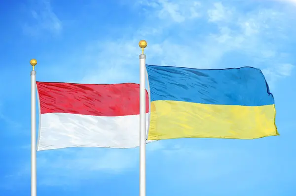 インドネシアとウクライナの旗竿と青空の背景に2つの旗 — ストック写真