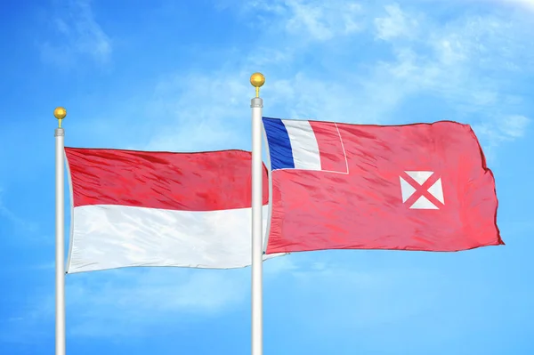 Indonesia and Wallis and Futuna two flags on flagpoles and blue cloudy sky background