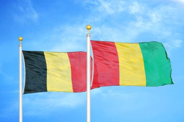 Belçika ve Gine bayrak direkleri ve mavi bulutlu arka planda iki bayrak