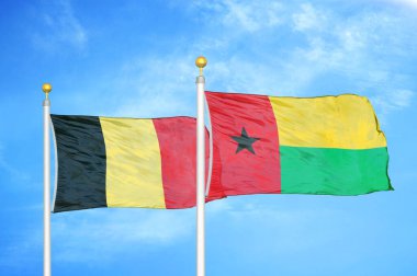 Belçika ve Gine-Bissau bayrak direğinde iki bayrak ve mavi bulutlu arka plan