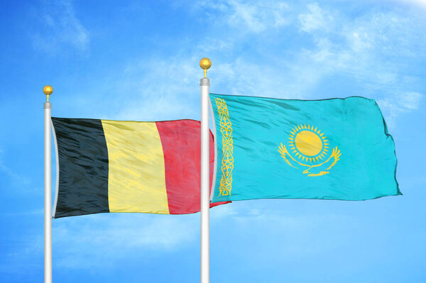 Бельгия и Казахстан - два флага на флагштоках и голубом облачном фоне неба
