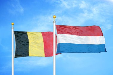 Belçika ve Hollanda bayrak direkleri ve mavi bulutlu arka planda iki bayrak