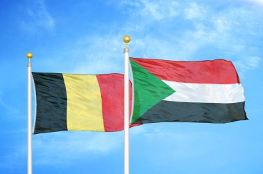 Belçika ve Sudan bayrak direkleri ve mavi bulutlu arka planda iki bayrak