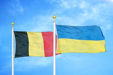 Belçika ve Ukrayna bayrak direkleri ve mavi bulutlu arka planda iki bayrak