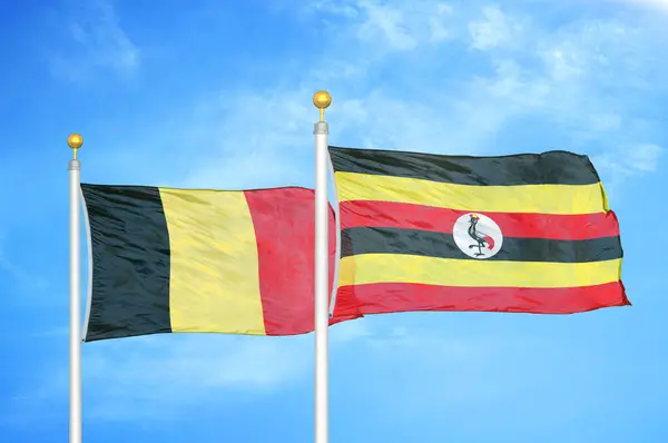 Bélgica Uganda Duas Bandeiras Postes Bandeira Azul Céu Nublado Fundo — Fotografia de Stock