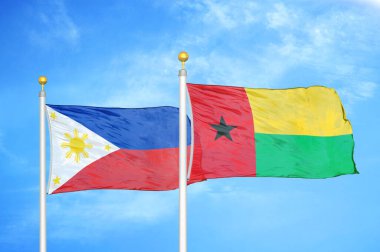 Filipinler ve Gine-Bissau bayrak direğinde iki bayrak ve mavi bulutlu arka plan