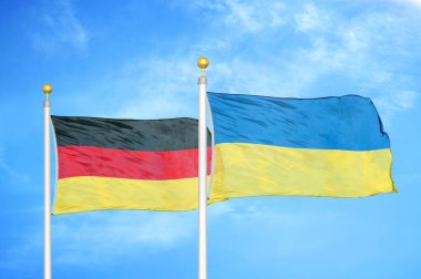 Almanya ve Ukrayna bayrak direkleri ve mavi bulutlu arka planda iki bayrak